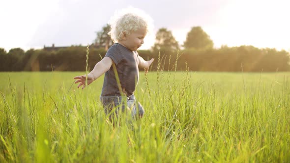  Baby Boy Playing with the Grass Around Him with a Smile