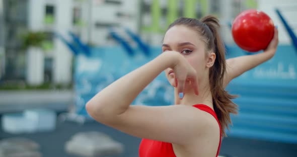 Portrait of Woman in Red Sports Costume Performing Callisthenics Exercises with Gymnastic Ball