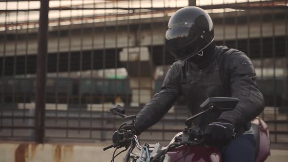 Young Attractive Man Motorcyclist with His Helmet and Custom Motorcycle on Street