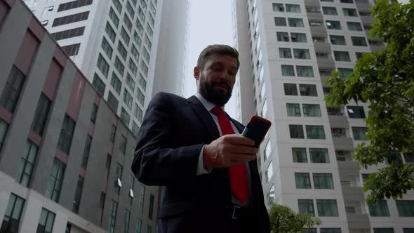 A Business Man Texting Phone in the Street