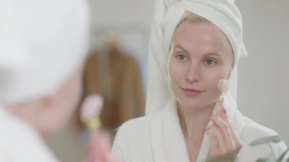 Pretty Female Doing Facial Massage in Bright Bathroom