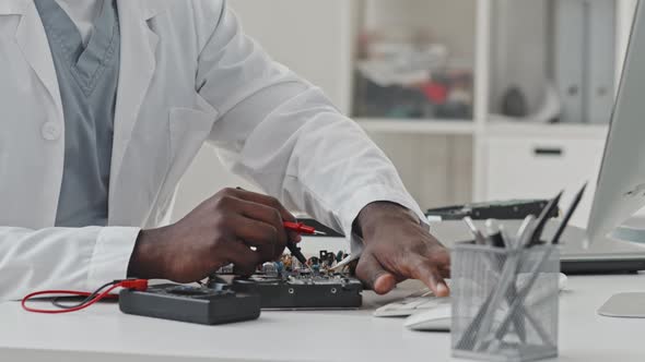 Hands of Electronics Engineer Working with Multimeter and Computer