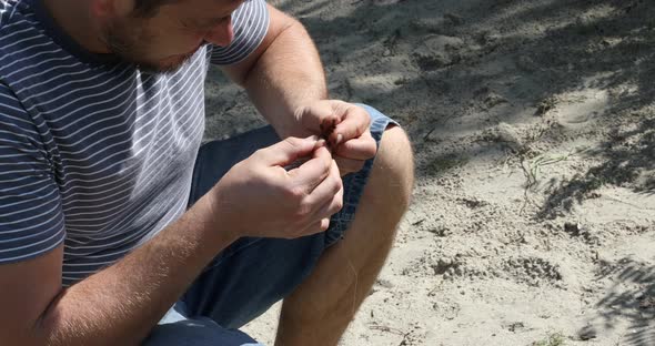 Fishing day. Fisherman puts bait on a fishing rod hook