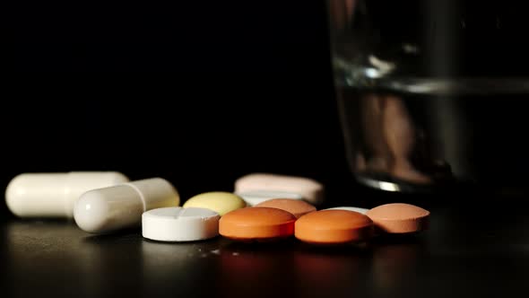 Time-Lapse: Man's Fingers Take White Pills One By One And Transparent Glass Of Water Rises