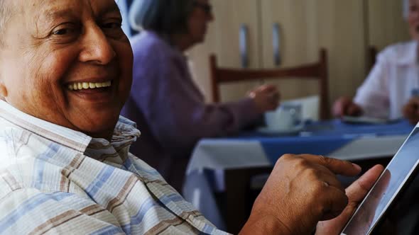 Senior man using digital tablet with his friends sitting in background 4k