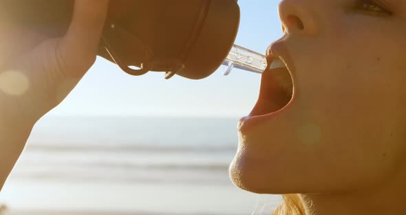 Fit woman drinking water in the beach