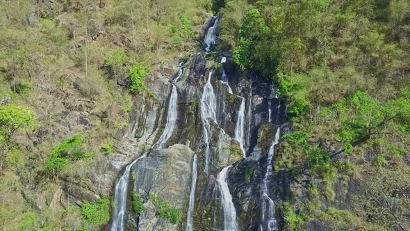 Drone Hangs Above High Waterfall Among Rocks in Highland