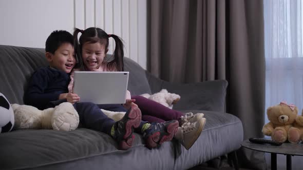 Laughing Chinese Kids Watching Cartoons on Tablet
