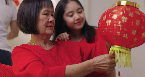 Asian Grand Mother And Grand Daughter Decorate House For Chinese New Year Celebrations