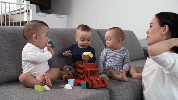 Asian Triplet Babies Playing with Wooden Toys on Couch