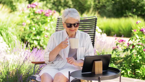 Happy Senior Woman with Tablet Pc at Summer Garden