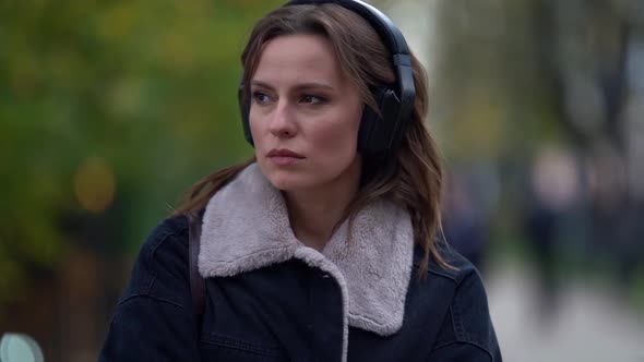 Close-up Portrait of a Sad Beautiful Young Woman Listening To Music in Black Headphones While