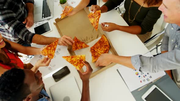 Happy executives sharing pizza in conference room at office