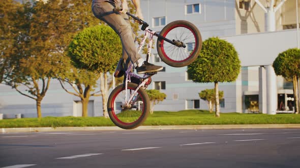 Young Male Bmx Rider is Jumping and Turning Handlebars of His Bicycle Doing Tricks on Parking Lot of