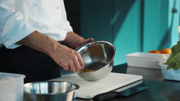 Professional restaurant kitchen: Chef whisking eggs in a bowl