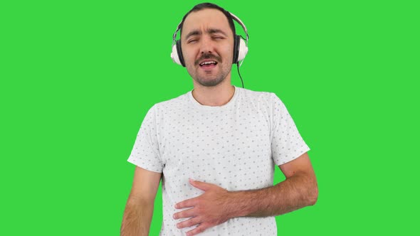 Happy Guy with Mustache Listening To the Music in Big White Headphones on a Green Screen, Chroma Key