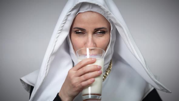 Closeup of Woman in Nun Costume Enjoying Taste of Milk Licking Lips Looking at Camera Smiling