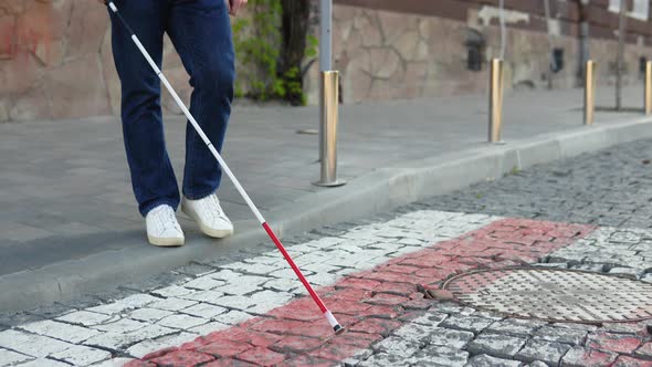 A Blind Man with a Cane Crosses the Road