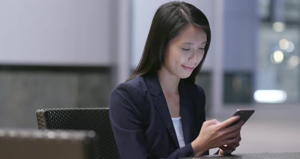 Businesswoman using smart phone in city at night 