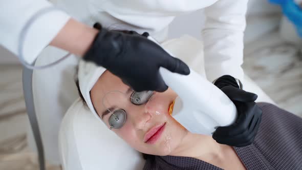 Aesthetic Procedure in Modern Cosmetology Clinic Expert Beautician is Using Phototherapy Apparatus