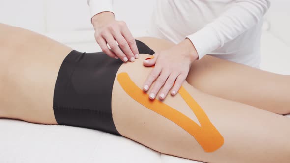 Therapist is applying kinesio tape to female body. Physiotherapy, kinesiology and recovery.