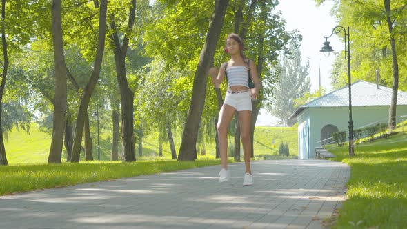 Wide Shot of Joyful African American Girl in Headphones Dancing on Park Alley in Sunny Summer Day