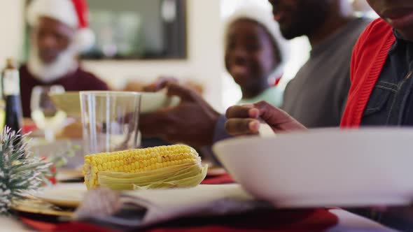 African american girl serving food in plate while sitting on dining table having lunch together at h