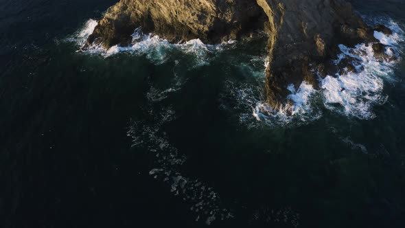 Aerial top view of Cliff. Waves crashing against the Rocks. Flying up above Sea Coast.