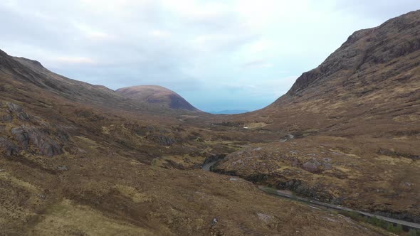 Aerial view of a valley in the Highlands with a road that winds through the m