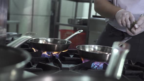 Chef Heats Oil and Puts Garlic Into Pan on Stove in Kitchen