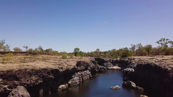 Drone flying above rocky gorge. Camera titls down and pans slightly to look down into gorge. Locatio