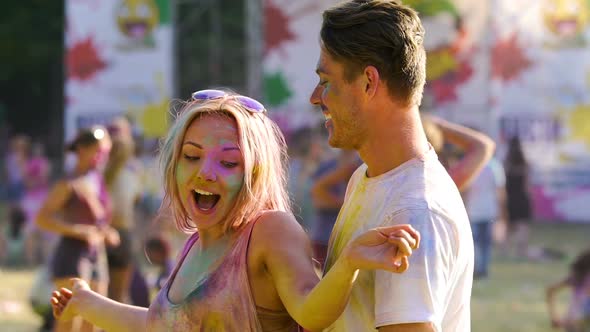 Beautiful Blonde Girl Flirting and Dancing With Her Boyfriend at Color Festival