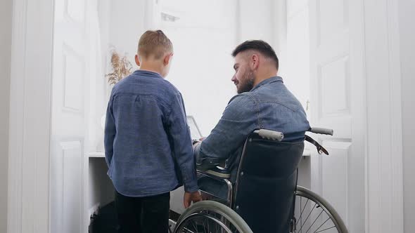 Bearded Man in Wheelchair which Talking with His Positive Smiling 8-Aged Son