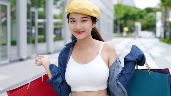 Smiling young Asian woman with shopping colour bags