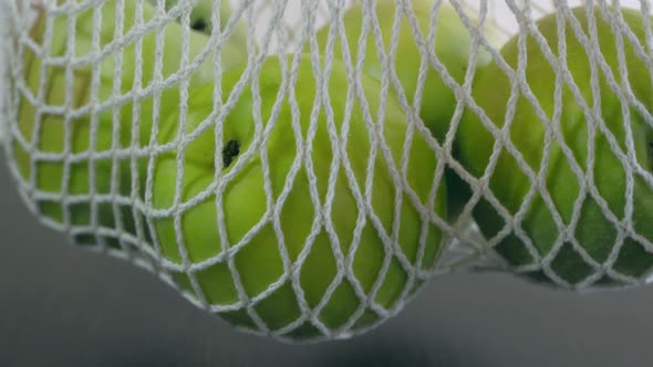 Closeup Shot of a White Net for Vegetables and Fruits with Large Green Apples