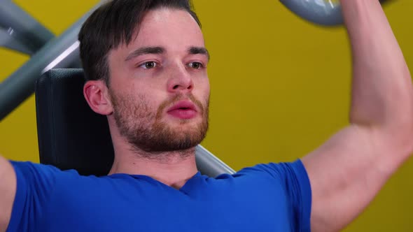 A Young Fit Man Trains on a Machine in a Gym - Closeup