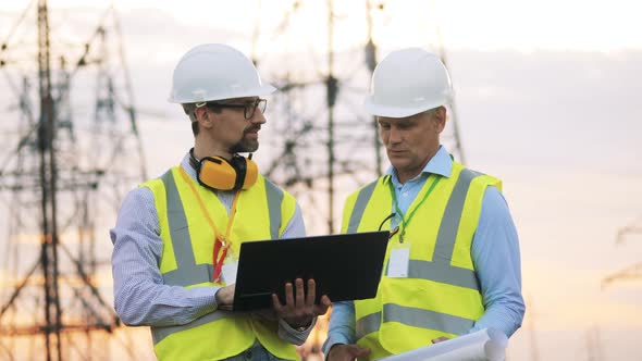 Two Powermen Are Talking Outside Near Electrical Towers