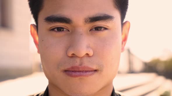 Outdoor Portrait of an Asian Man Looking at the Camera with a Serious Face and Intense Look