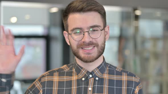 Portrait of Young Designer Doing Video Chat and Waving