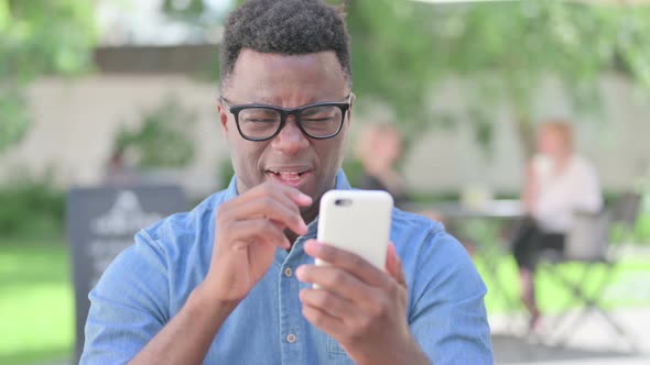 Portrait of African Man Reacting to Loss on Smartphone