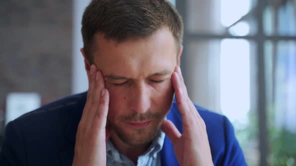 Young Man Suffering From Headache in Office