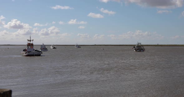 Fishing boats bobbing up and down on lazy waves as the tide rolls into Orford estuary on the Suffolk