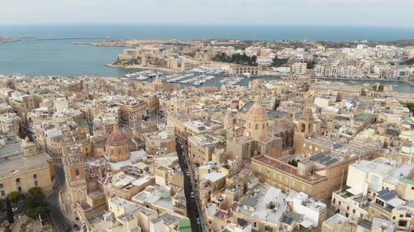 Pull back reveal 4k drone footage of the cityscape of the 'Three Cities of Malta' along the coast