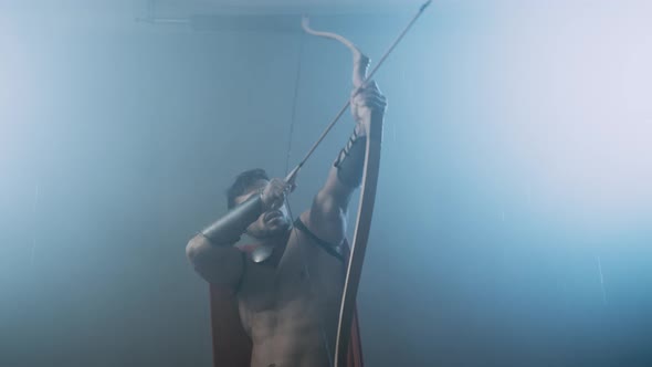 Shirtless Wet Spartan Raising Bow with Arrow Up.