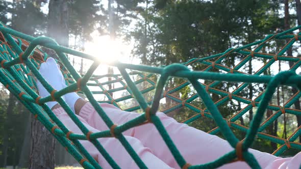 Legs of a Girl Lying in a Hammock in the Woods