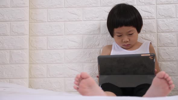 Cute little boy using tablet computer at home.