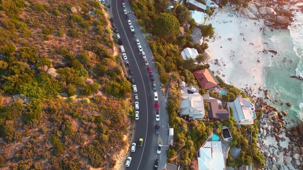 top down view of cars driving on Clifton Beach Road during sunset in Cape Town, aerial