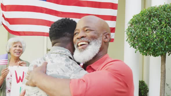 African american male soldier embracing his smiling father over family and american flag