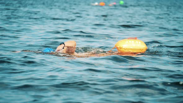Professional Swimmer Swimming with a Floating Bag in a River