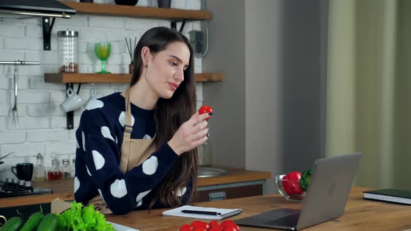 Woman chef teaches online video call laptop shows ingredients webcam in kitchen